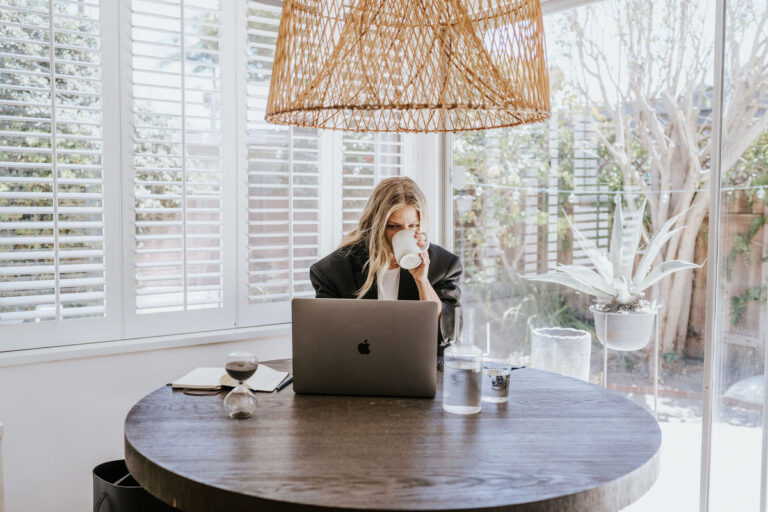 woman drinking coffee working on laptop